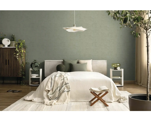 Modernes Schlafzimmer mit grüner Wand, weißem Bett, Pendelleuchte und hellem Teppich in organisierter, natürlicher Atmosphäre.