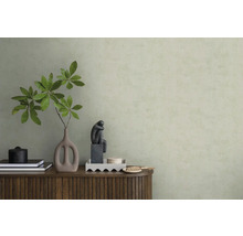 Strukturierte hellgrüne Tapete hinter einem Sideboard aus Holz mit Vase, Zweigen und Skulptur in einem minimalistischen Raum.