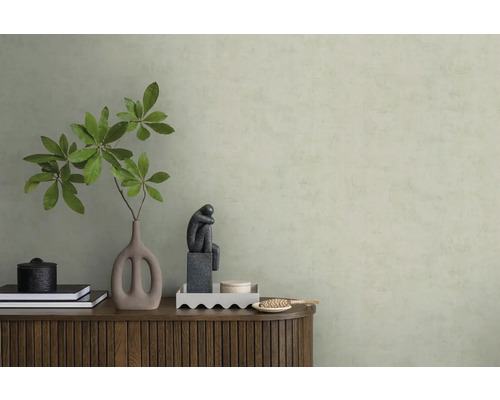 Strukturierte hellgrüne Tapete hinter einem Sideboard aus Holz mit Vase, Zweigen und Skulptur in einem minimalistischen Raum.