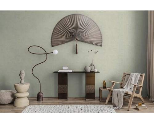 Modern gestaltetes Zimmer mit hellgrüner Wandfarbe, einem großen dekorativen Fächer, einem Konsolentisch und einem geflochtenen Sessel.