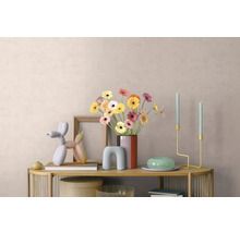 Hell dekorierter Konsolentisch mit Gerbera-Vase, Bilderrahmen, Ballonhund-Skulptur und minimalistischen Kerzenhaltern vor einer strukturierten Wand.