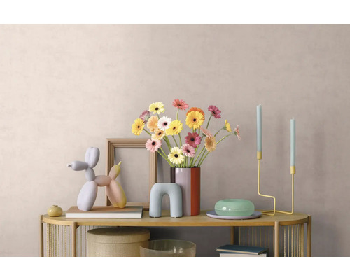 Hell dekorierter Konsolentisch mit Gerbera-Vase, Bilderrahmen, Ballonhund-Skulptur und minimalistischen Kerzenhaltern vor einer strukturierten Wand.