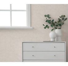Helle, strukturierte Tapete in einem modernen Raum mit weißer Kommode, Fenster und Eukalyptuszweigen in weißen Vasen.