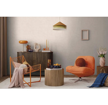 Modernes Wohnzimmer mit orangem Polstersessel, orangem Drahtstuhl, Sideboard aus dunklem Holz, runden Holztischen und einer Pendelleuchte.