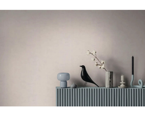 Moderne Wohndekoration mit einer Vogelfigur, einer Marmorvase mit einem Baumwollzweig und Kerzenhaltern auf einer geriffelten Oberfläche.
