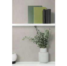 Strukturierte Wand mit weißen Regalböden, Büchern, einer Vase mit Eukalyptuszweigen und einem runden Dekoelement.