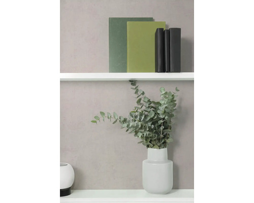 Strukturierte Wand mit weißen Regalböden, Büchern, einer Vase mit Eukalyptuszweigen und einem runden Dekoelement.