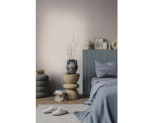 Modernes Schlafzimmer mit blauem geripptem Kopfteil, skulpturalem Beistelltisch aus Holz, dekorativer Vase und strukturierten Wänden.