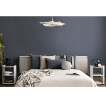 Modernes Schlafzimmer mit Bett, diversen Kissen, einer Pendelleuchte und Nachttischen vor einer strukturierten Wand.