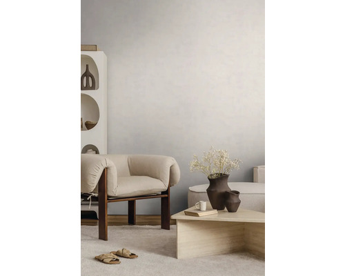 Helles Wohnzimmer mit strukturierter Wandgestaltung, modernem Holzsesssel, Steincouchtisch und hellem Teppich.