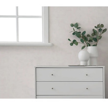 Heller Raum mit weißem Fenster, einer hellen Wand und weißer Kommode, dekoriert mit Vasen und Eukalyptuszweigen.