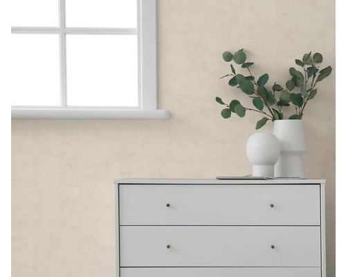 Strukturierte beige Tapete in hellem Raum neben weißem Fenster und weißer Kommode mit Vasen und Eukalyptuszweigen.