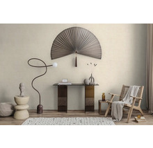 Helles minimalistisches Zimmer mit fächerförmiger Wanddekoration, Glastisch, geschwungener Stehlampe und Holzsessel auf strukturiertem Teppich.