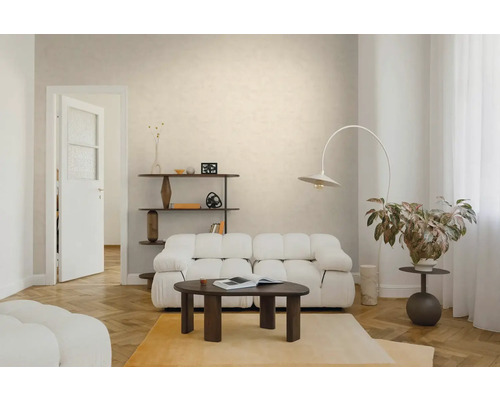 Hell eingerichtetes Wohnzimmer mit weißem Polstersofa, dunklem Couchtisch aus Holz, Bogenlampe und Parkettboden in Fischgrätoptik.