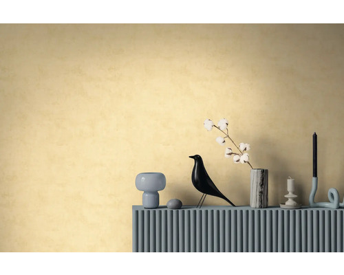 Strukturierte Tapete in warmem Gelb an einer Wand hinter einem Sideboard mit dekorativer Vogelfigur, Vase mit Baumwollzweig und Kerzenhaltern.