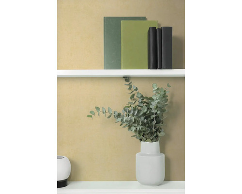 Strukturierte ockerfarbene Tapete in modernem Interieur mit weißen Regalen, Büchern und einer Vase mit Eukalyptus.