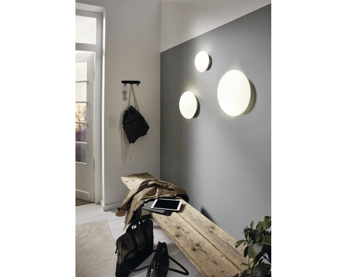 Heller Eingangsbereich mit Holzhocker, Wandleuchten und Garderobe