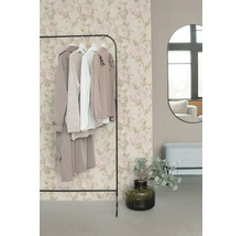 Vliestapete mit romantischem Rosenmuster in Beige und Rosa hinter einem Kleiderständer in einem modern eingerichteten Ankleidezimmer.