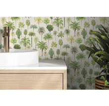 Vliestapete mit Palmenmotiven in einem hellen Badezimmer hinter einem weißen Waschbecken und einem Holzunterschrank.