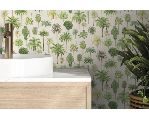 Vliestapete mit Palmenmotiven in einem hellen Badezimmer hinter einem weißen Waschbecken und einem Holzunterschrank.