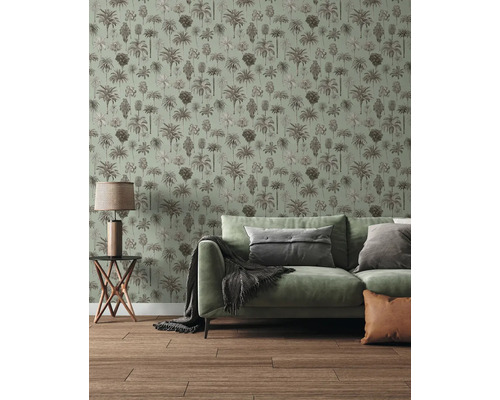 Vliestapete mit Palmen-Muster in einem hellen Wohnzimmer mit grünem Sofa und Holzboden.