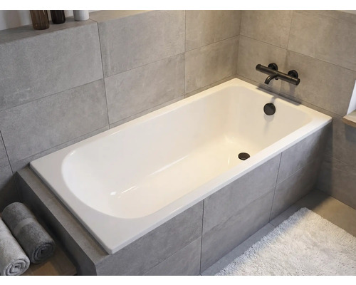 Eingebaute Badewanne im Badezimmer mit Armatur und Handtüchern