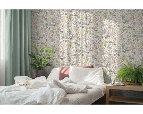 Helles Schlafzimmer mit einer Katze auf dem weißen Bett, Blumentapete im botanischen Stil, grünen Vorhängen und Zimmerpflanzen.
