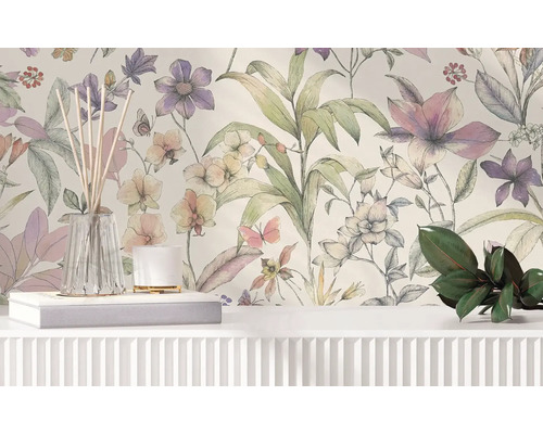 Vliestapete mit floralem Muster aus großen Blumen und Blättern im Aquarellstil hinter einem weißen Sideboard mit Dekoration.