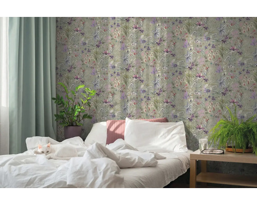 Schlafzimmer mit floraler Vliestapete, weißem Bett mit Katze, Zimmerpflanzen und hellem Vorhang.