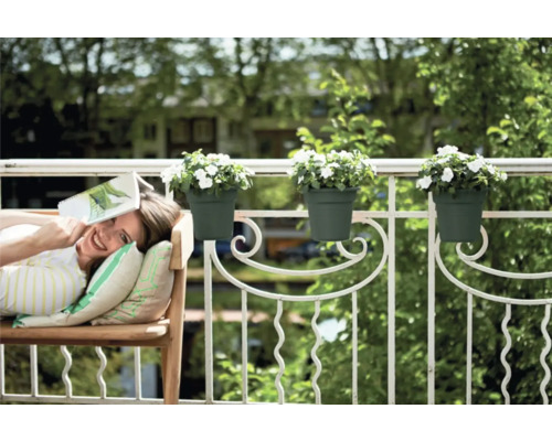 Frau entspannt auf dem Balkon mit Blumenkästen am Geländer
