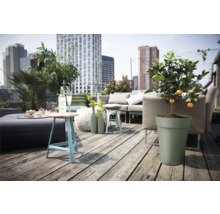 Eine Dachterrasse mit einer Sitzgruppe, einem Tisch, Pflanzen und Blick auf die Stadt.