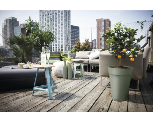 Eine Dachterrasse mit einer Sitzgruppe, einem Tisch, Pflanzen und Blick auf die Stadt.