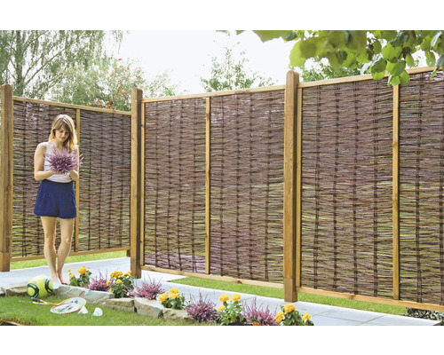 Gartenszene mit Weidenzaun und Frau mit Blumenstrauß