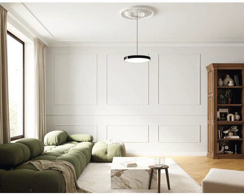 Wohnzimmer mit grüner Couch, Couchtisch, Bücherregal und Pendelleuchte