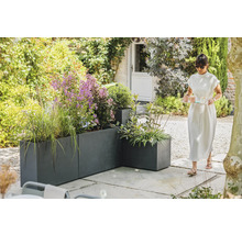 Gartenansicht mit grauen Pflanzgefäßen und einer Frau, die ein Tablett trägt