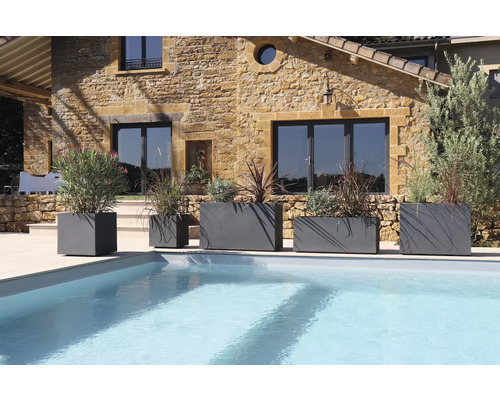 Szene mit mehreren grauen Pflanzgefäßen unterschiedlicher Größe neben einem Swimmingpool.