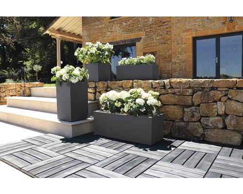 Außenaufnahme von rechteckigen und quadratischen Pflanzkästen mit Blumen vor einem Gebäude.