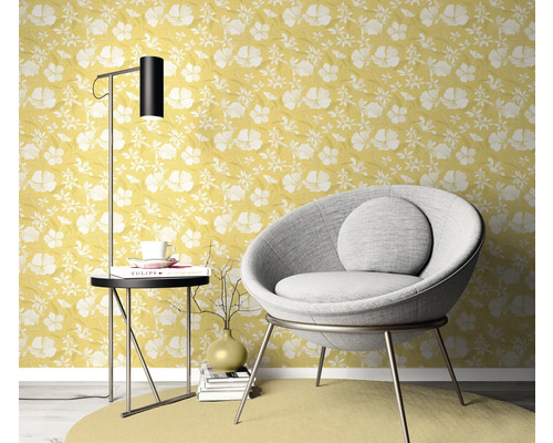 Wohnszene mit gelber Blumentapete, Sessel, Stehlampe und Beistelltisch