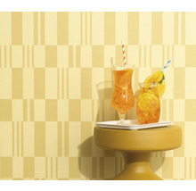 Zwei Getränke mit Strohhalm und Orangenscheiben auf einem kleinen Tisch vor gemusterter Wand.