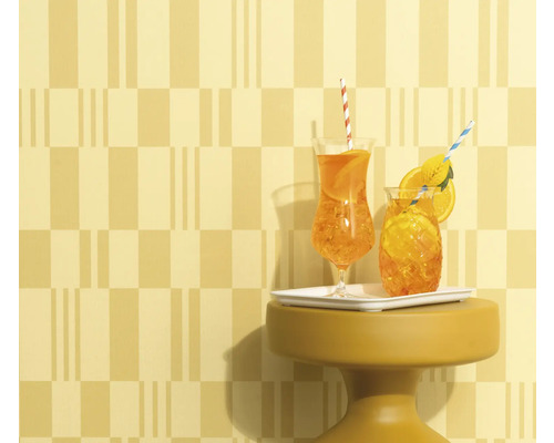 Zwei Getränke mit Strohhalm und Orangenscheiben auf einem kleinen Tisch vor gemusterter Wand.