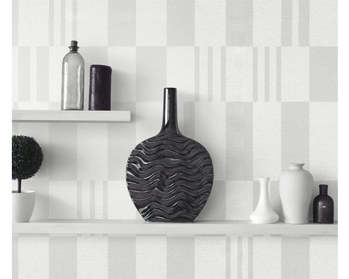 Dekorative Vasen auf weißen Regalen vor gemusterter Wand