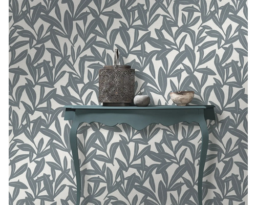 Dekoratives Interieur mit einem Tisch, einer Laterne und einer Wand mit Blattmuster Tapete.