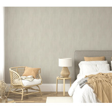 Schlafzimmer mit Bett, Beistelltisch, Lampe und Rattansessel