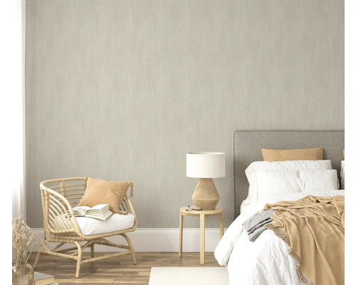 Schlafzimmer mit Bett, Beistelltisch, Lampe und Rattansessel
