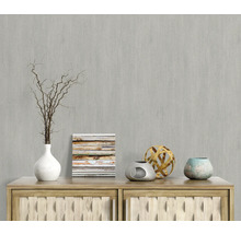 Dekorative Szene mit Vase, Zweigen, Bild und Zierobjekten auf einer Holzkommode vor einer grauen Wand