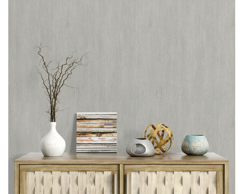 Dekorative Szene mit Vase, Zweigen, Bild und Zierobjekten auf einer Holzkommode vor einer grauen Wand