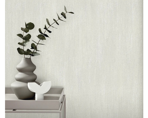Nahaufnahme einer strukturierten, hellen Tapete mit einer Vase mit Pflanzen auf einem Tisch