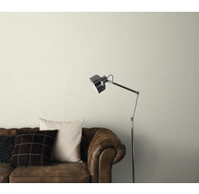 Gemusterte Tapete über einem braunen Ledersofa mit Stehlampe