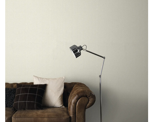 Gemusterte Tapete über einem braunen Ledersofa mit Stehlampe