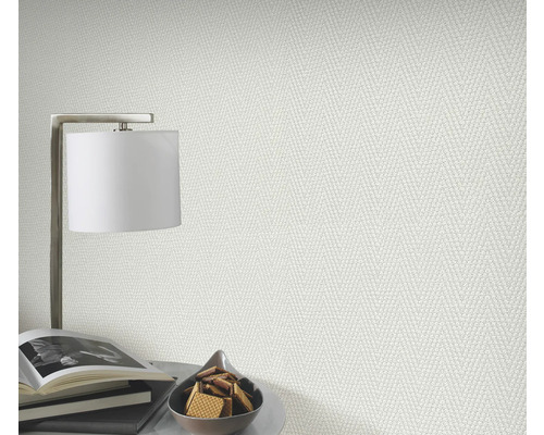 Nahaufnahme einer strukturierten Tapete in einem hellen Raum mit Lampe, Büchern und Gebäck